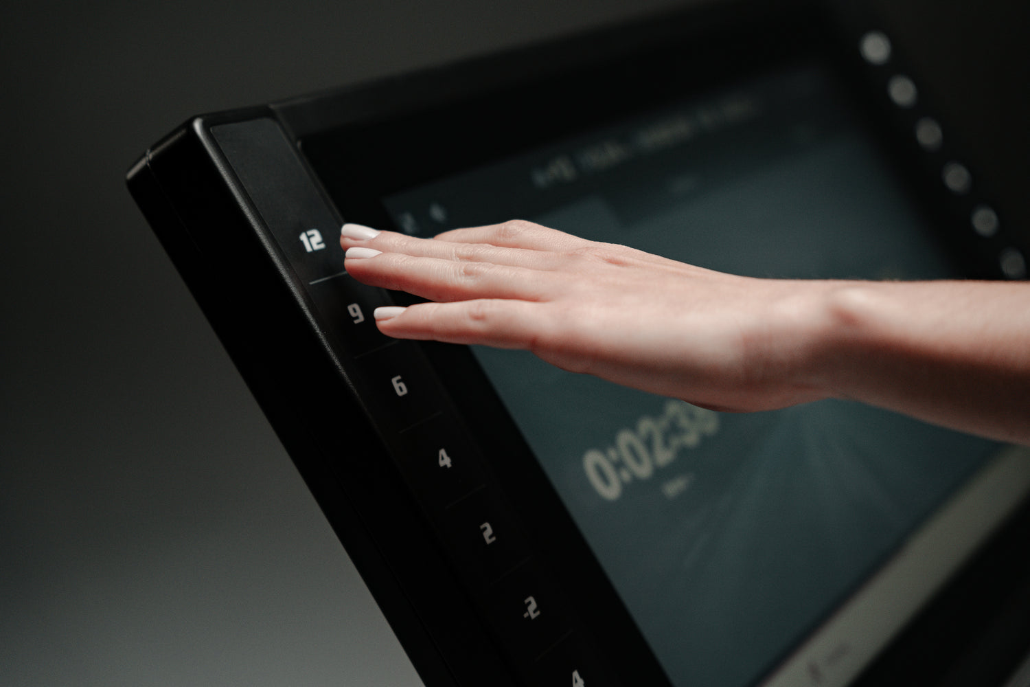 Close-up of hand adjusting speed on the SOLE treadmill touchscreen display