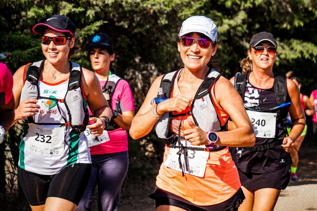 Group of women participating in a marathon, smiling as they run.