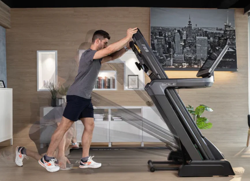Man folding the SOLE F89 Treadmill easily for compact storage in living room