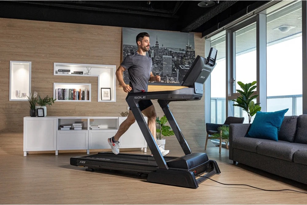 Man in dark athletic wear running on a SOLE F89 treadmill