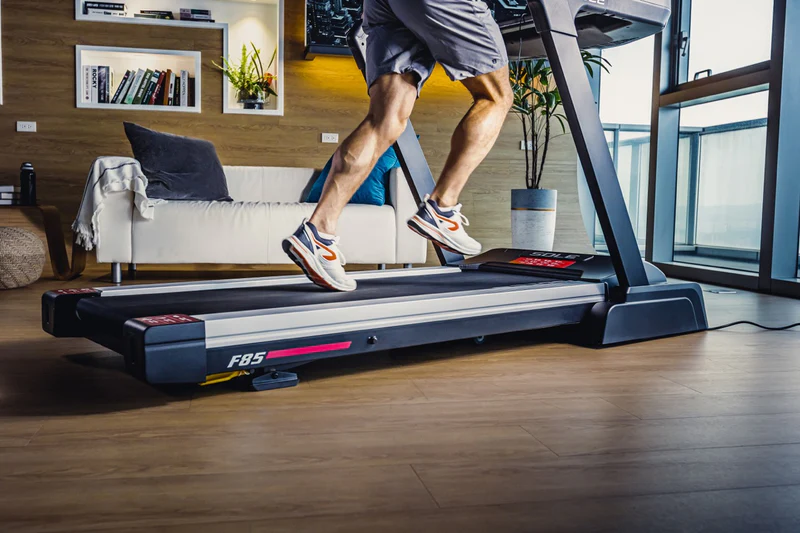 Person running on SOLE F85 treadmill in modern living room, highlighting the treadmill’s sturdy build and smooth operation.