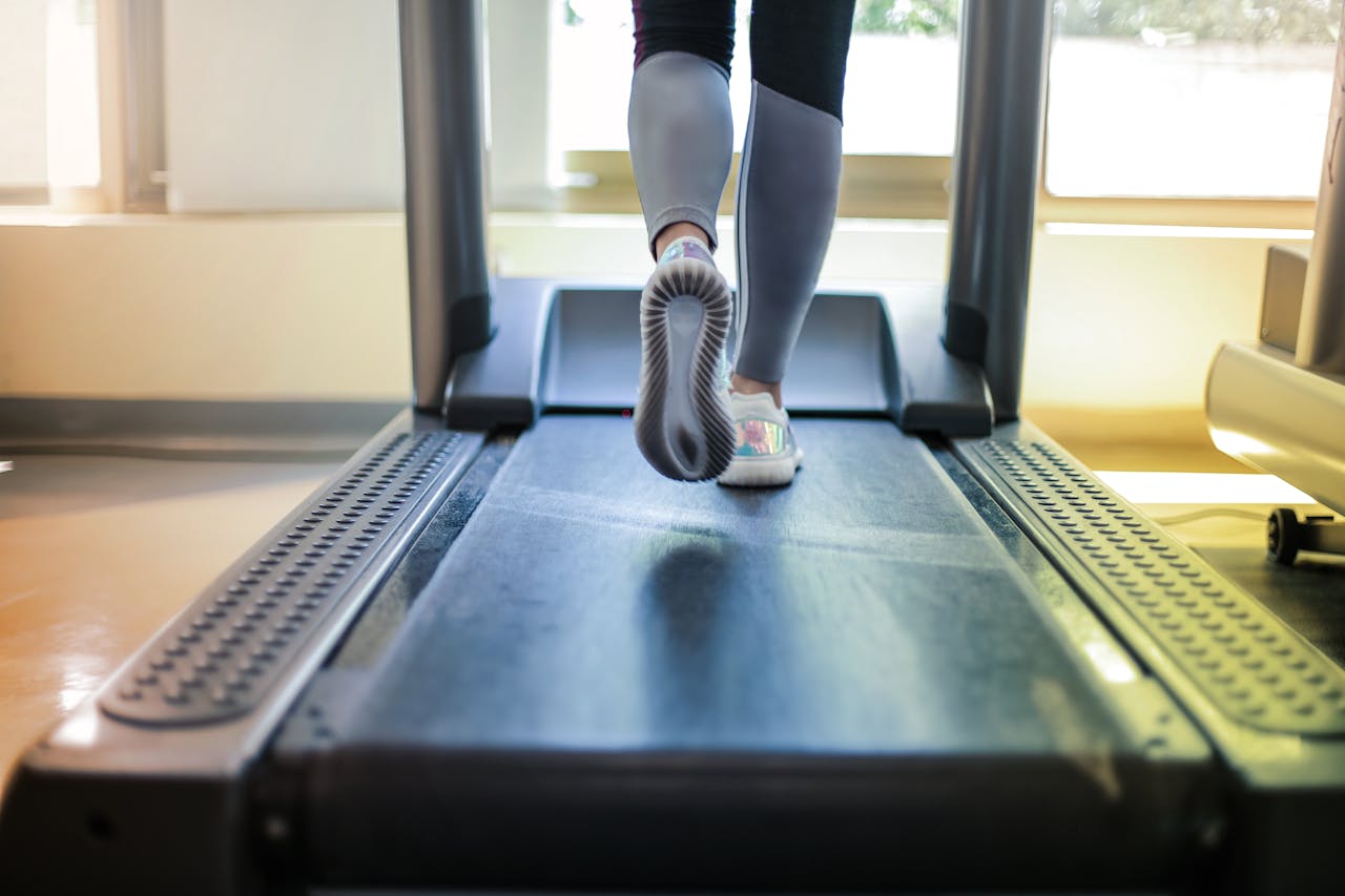 Person running on a treadmill with a focus on their feet and the treadmill belt.