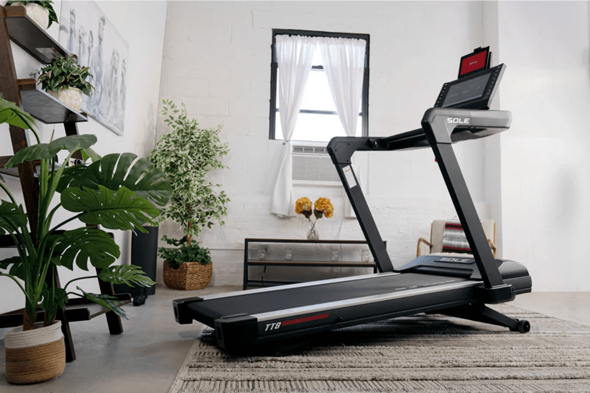 SOLE TT8 treadmill with a mounted touchscreen display, dual handrails, and a black and silver running deck shown from a side angle.
