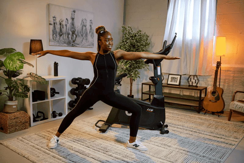 Woman doing yoga beside the SOLE LCB Exercise Bike.