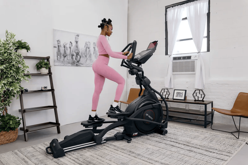 Woman exercising on the SOLE E98 elliptical, positioned in a bright, minimalistic room.