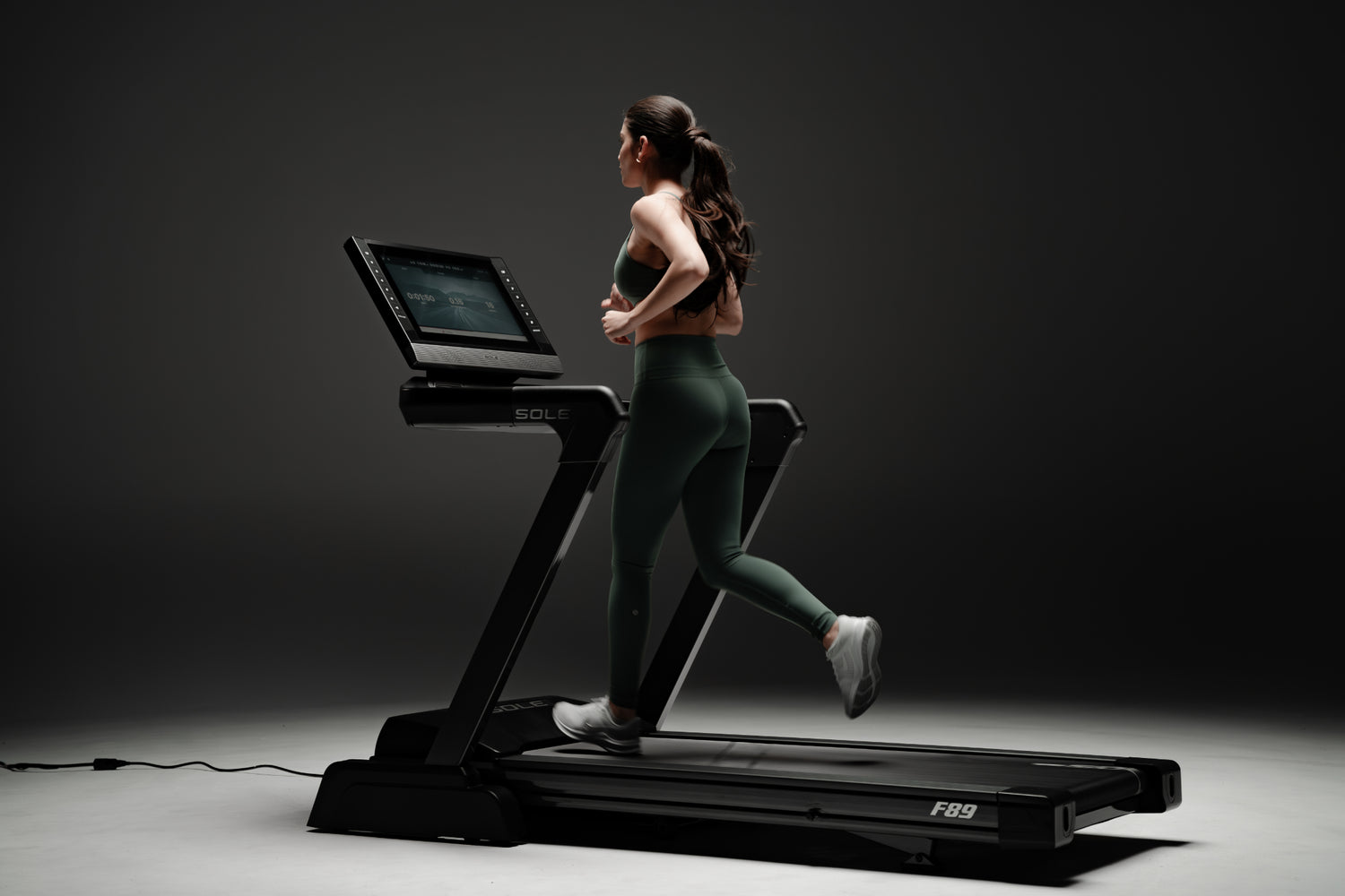 Woman running on a SOLE F89 treadmill, showcasing sleek design and advanced features for high-quality workout experience.
