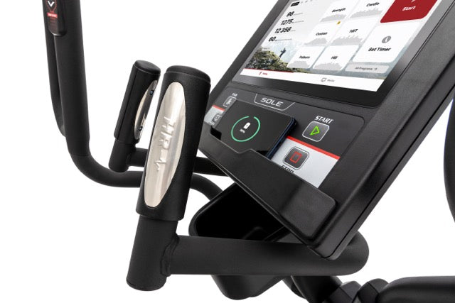 Detailed view of the Sole E98 elliptical machine's handle with chrome accents, touchscreen display showcasing fitness metrics, and control buttons, including the illuminated "SOLE" logo and start button, against a white background.