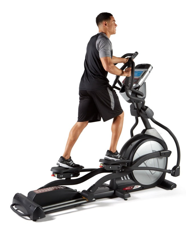 A man exercising on a SOLE Fitness elliptical, while monitoring his heart rate