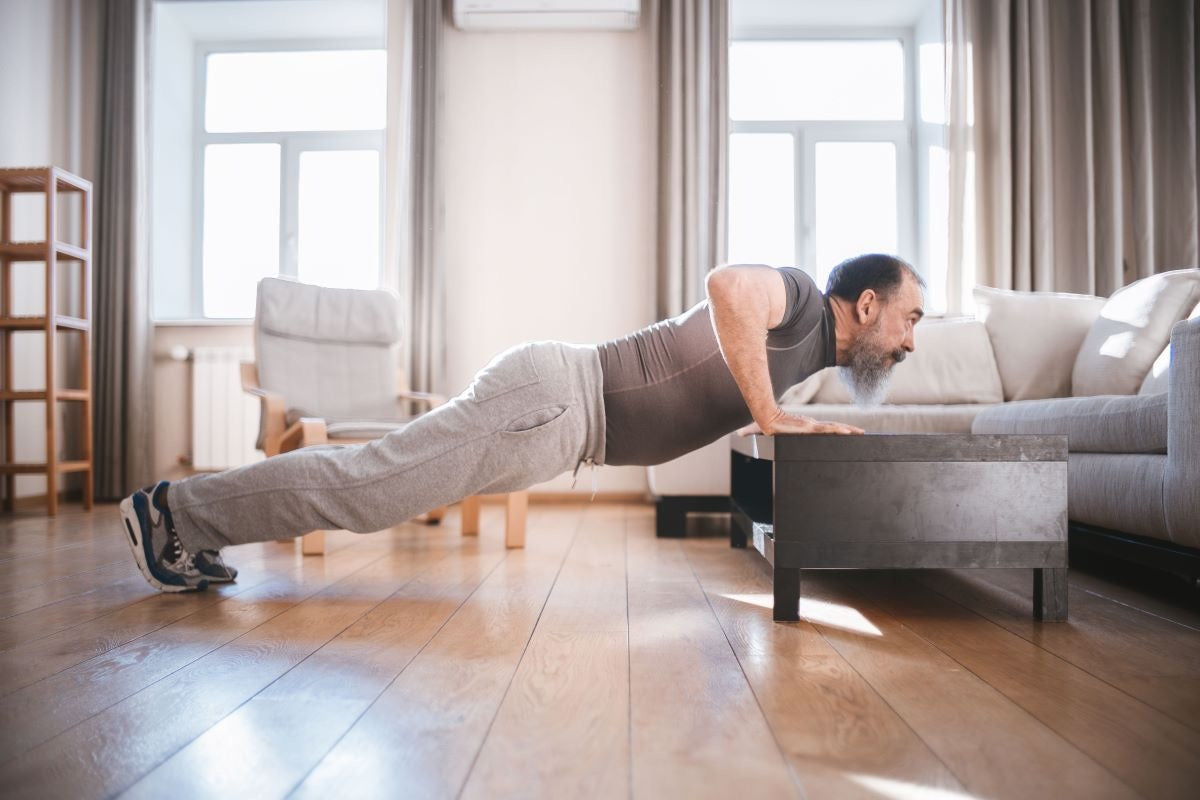 Man doing a push-up with his hands on a low table, body straight from head to heels