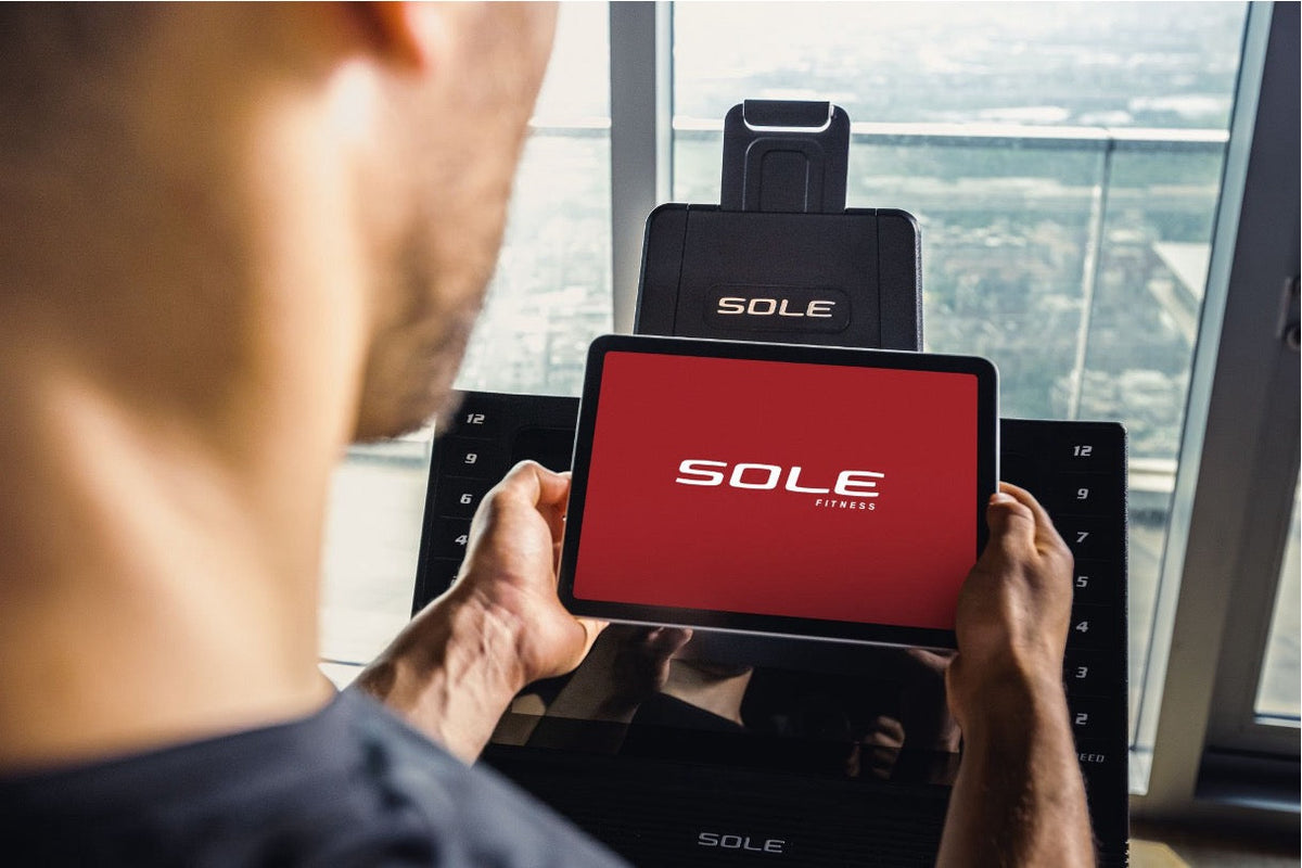 Man operating the touchscreen of the SOLE F85 treadmill
