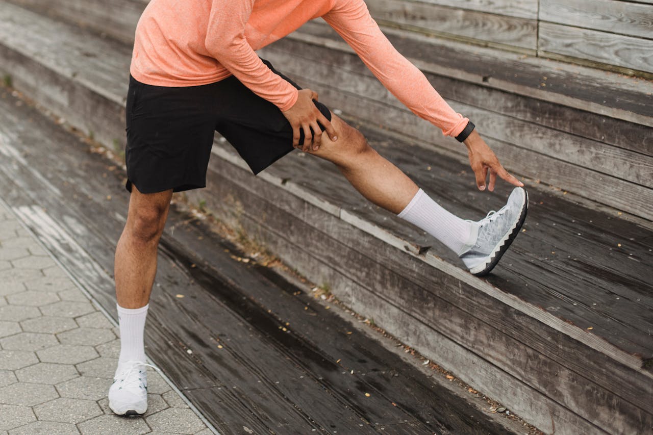 Person in athletic wear stretching their hamstring by placing one leg on a step.