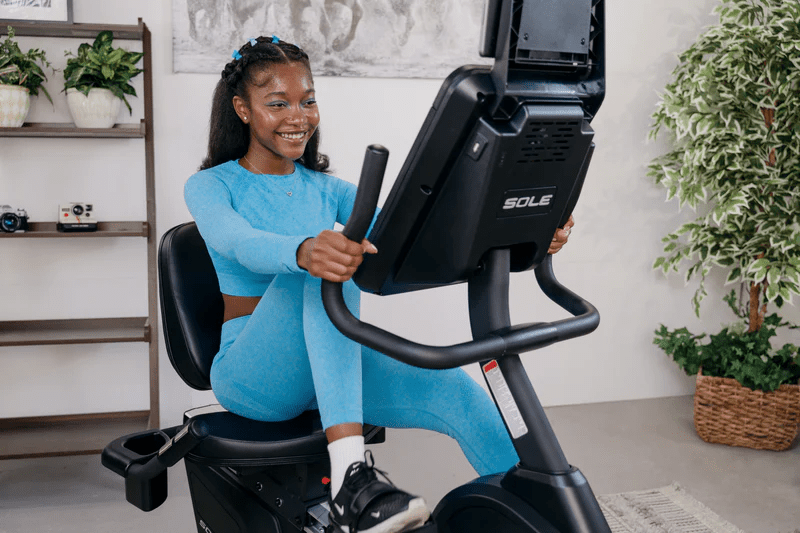 Woman riding the SOLE R92 Recumbent Bike.