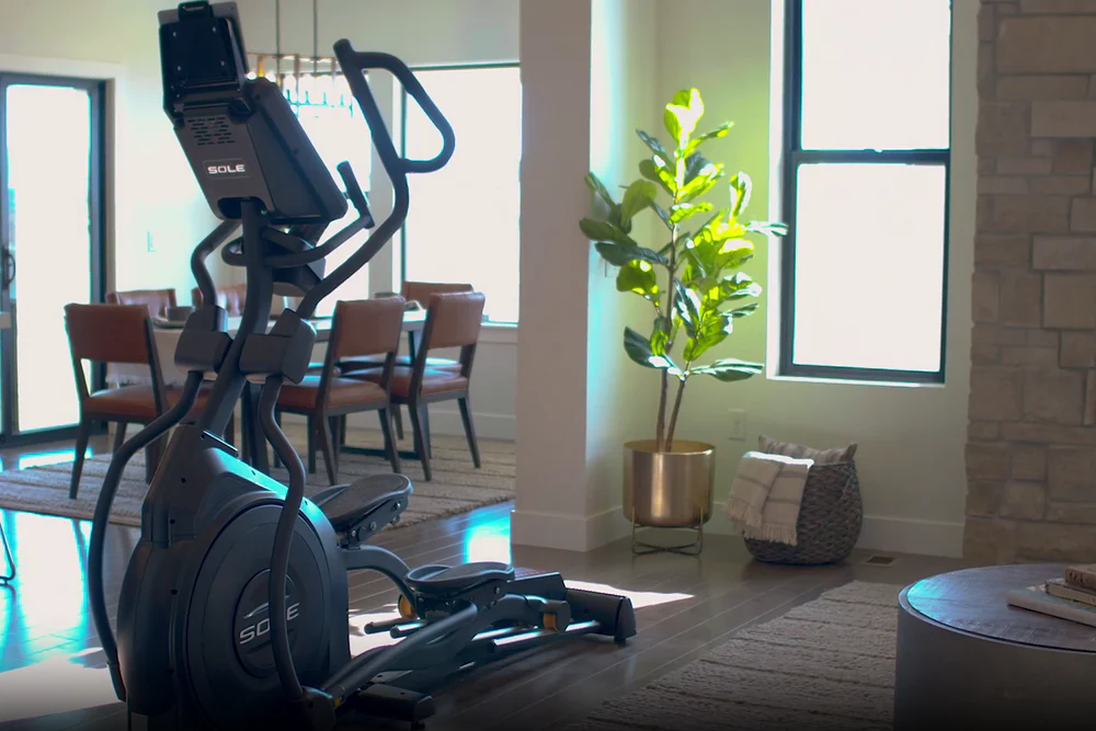 SOLE elliptical trainer set up in living room, showcasing sleek design and space-efficient placement