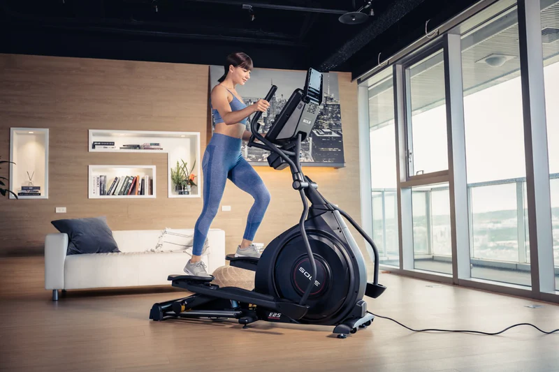 Woman exercising on SOLE E25 Elliptical, enjoying smooth pedaling for effective workout