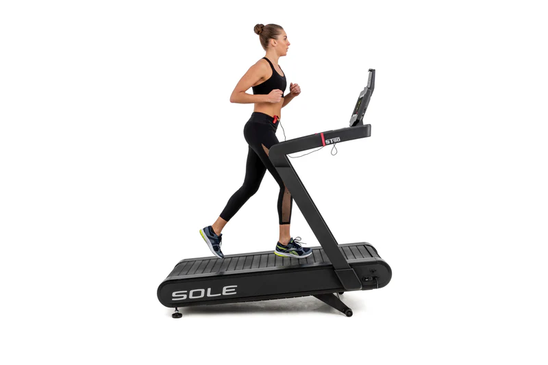 Woman running on a SOLE ST90 treadmill, focused on cardio workout.