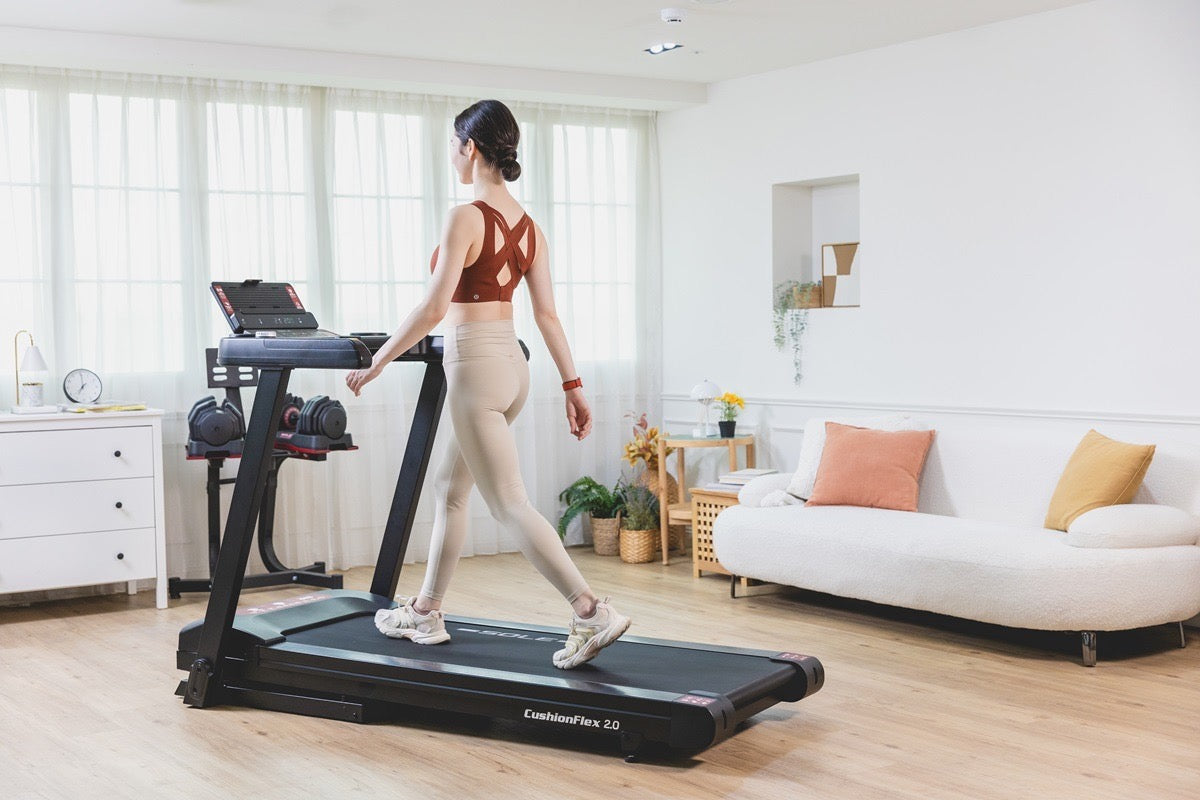 Woman walking on a SOLE treadmill with a CushionFlex 2.0 deck in a home living room