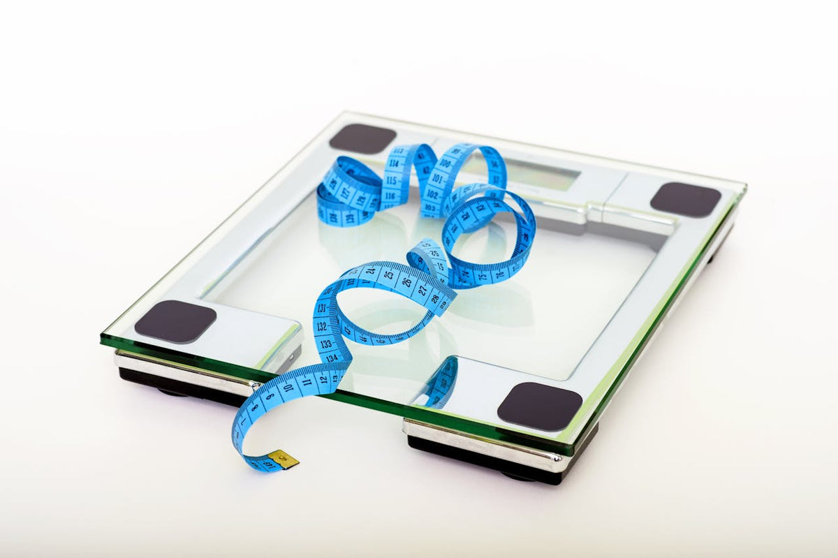 Glass bathroom scale and blue tape measure used to track treadmill weight loss progress