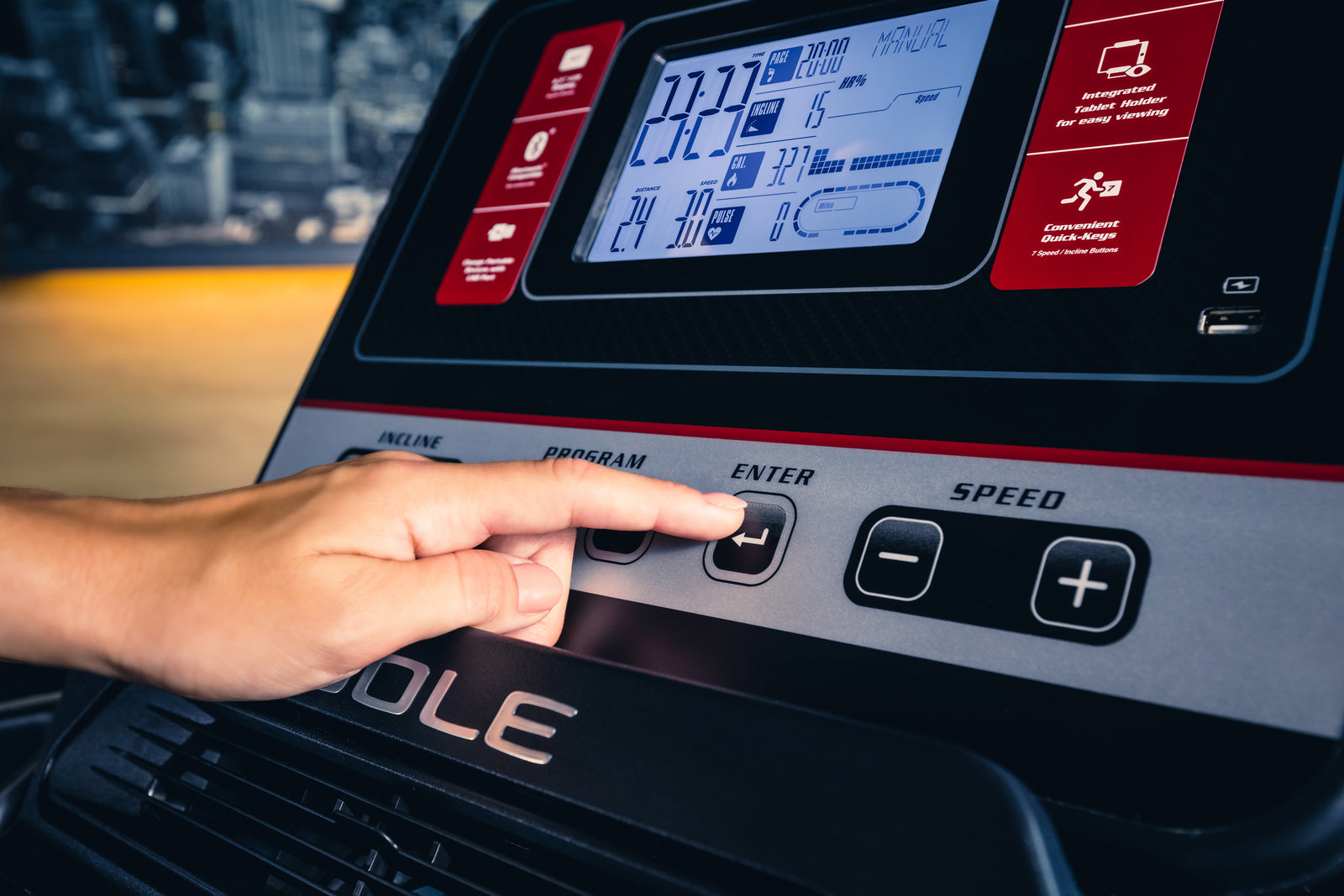 a hand pressing a button on a treadmill