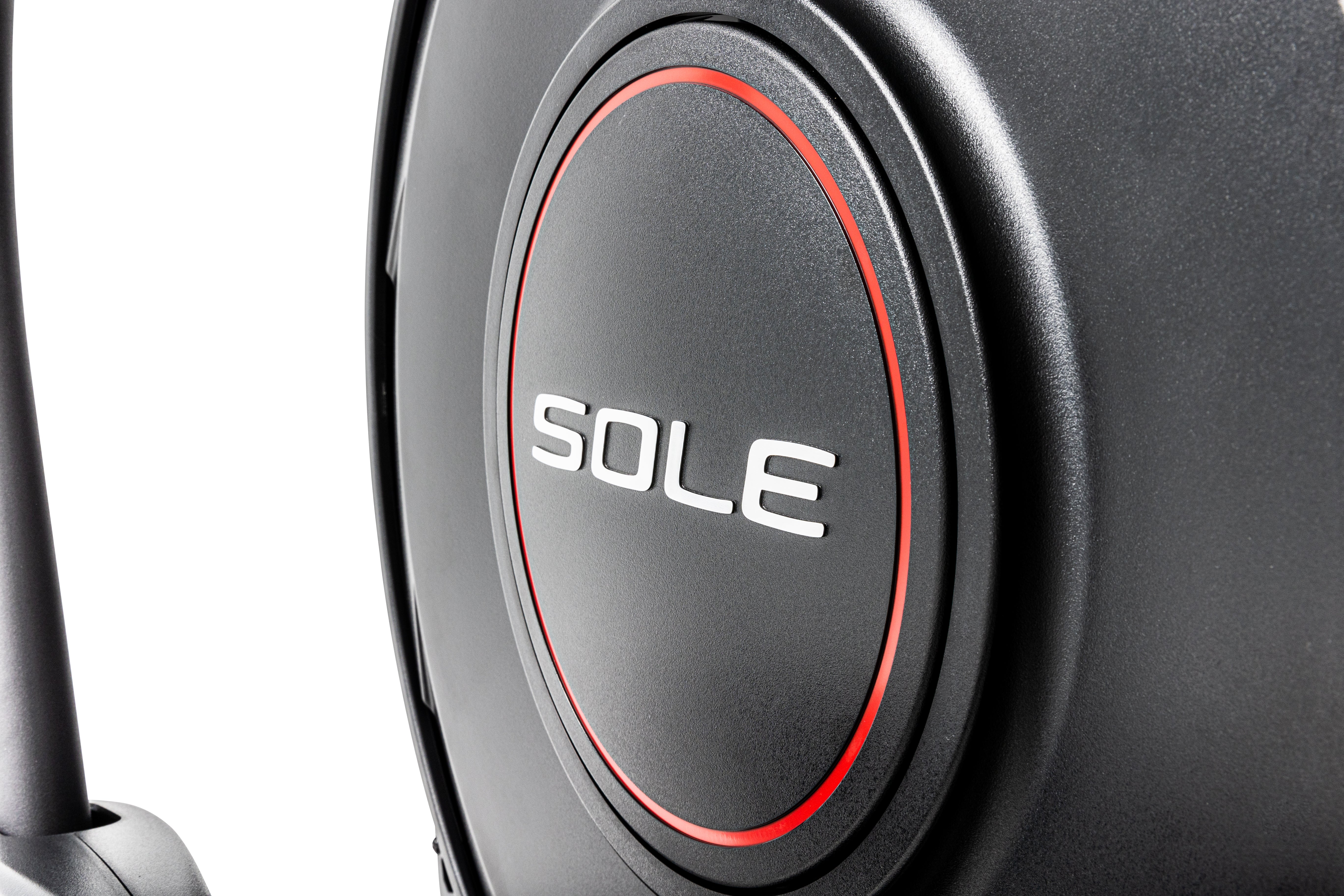 Close-up of the Sole E25 elliptical's black circular component with the brand name 'SOLE' in white letters, surrounded by a striking red outline.