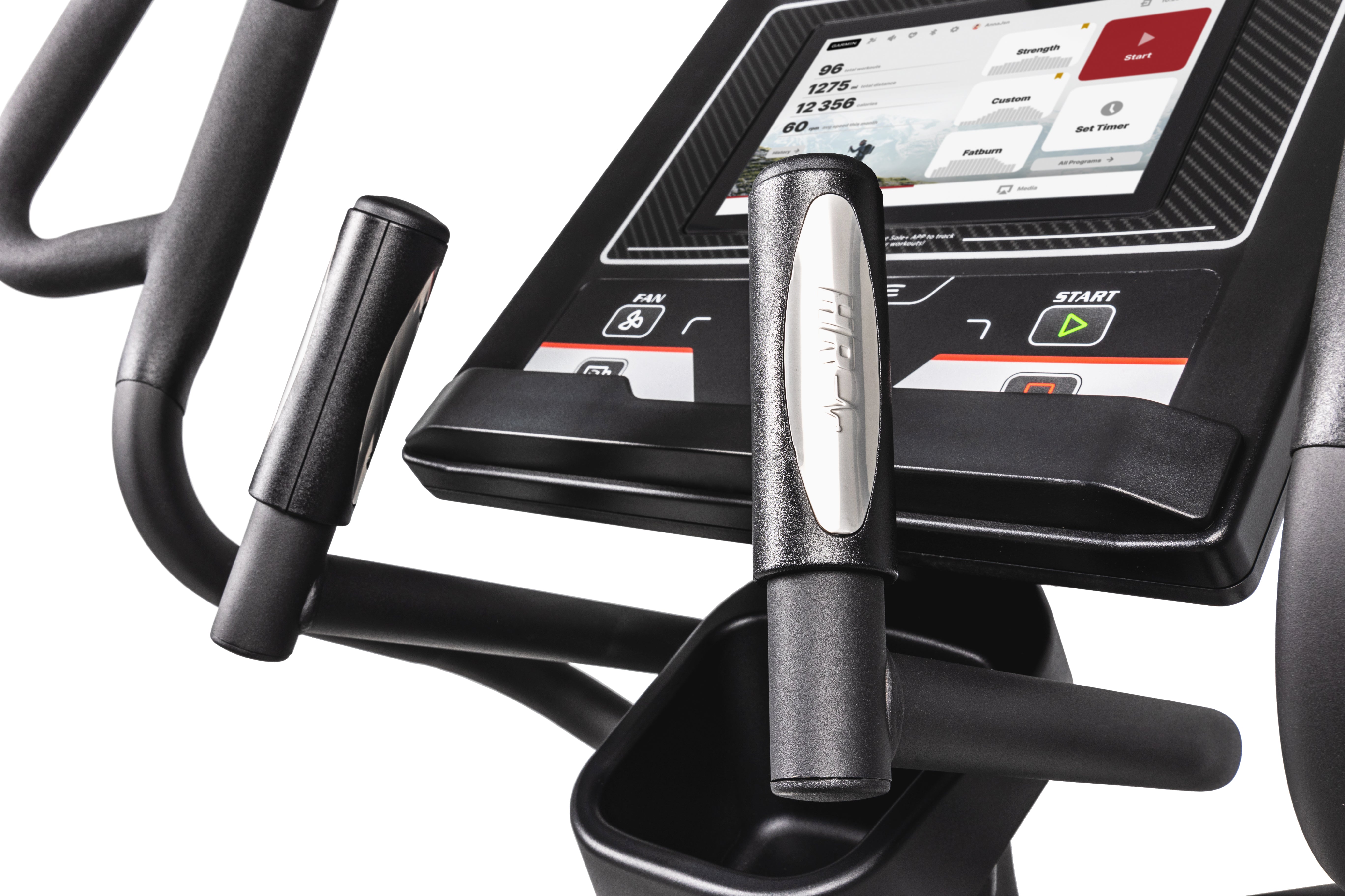 Detailed view of the Sole E35 elliptical machine's central console and handlebars. The console features a digital display showing workout metrics like distance, heart rate, and time. Below the screen are tactile buttons labeled with various controls, including start and stop. The handlebars, with padded grips, frame the console, and one handle showcases a silver Sole logo. The bottom of the frame also reveals a black storage tray.
