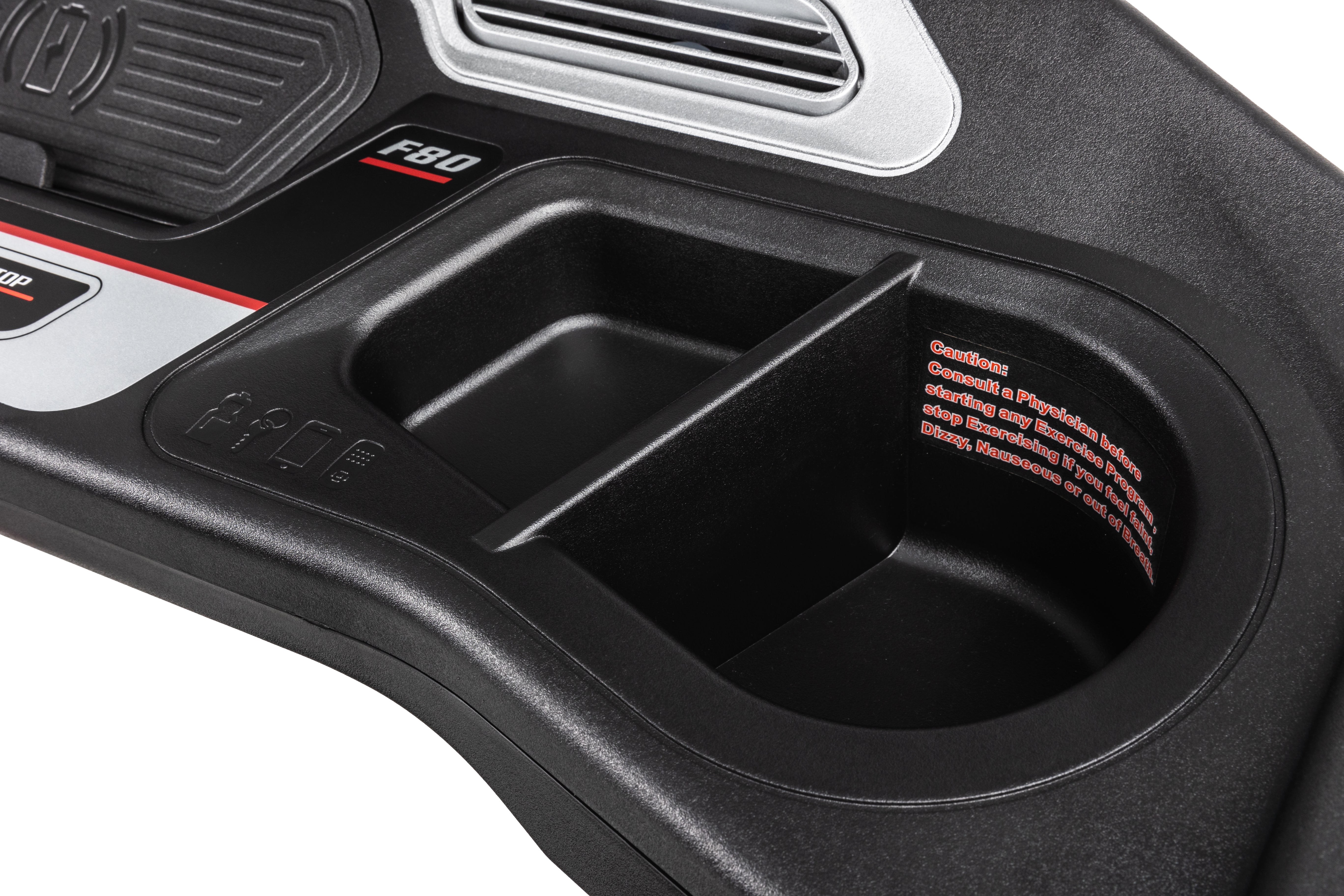 Detail of the Sole F80 treadmill's console, showcasing the labeled 'F80' logo, a recessed storage compartment, and printed safety instructions on the inner surface.