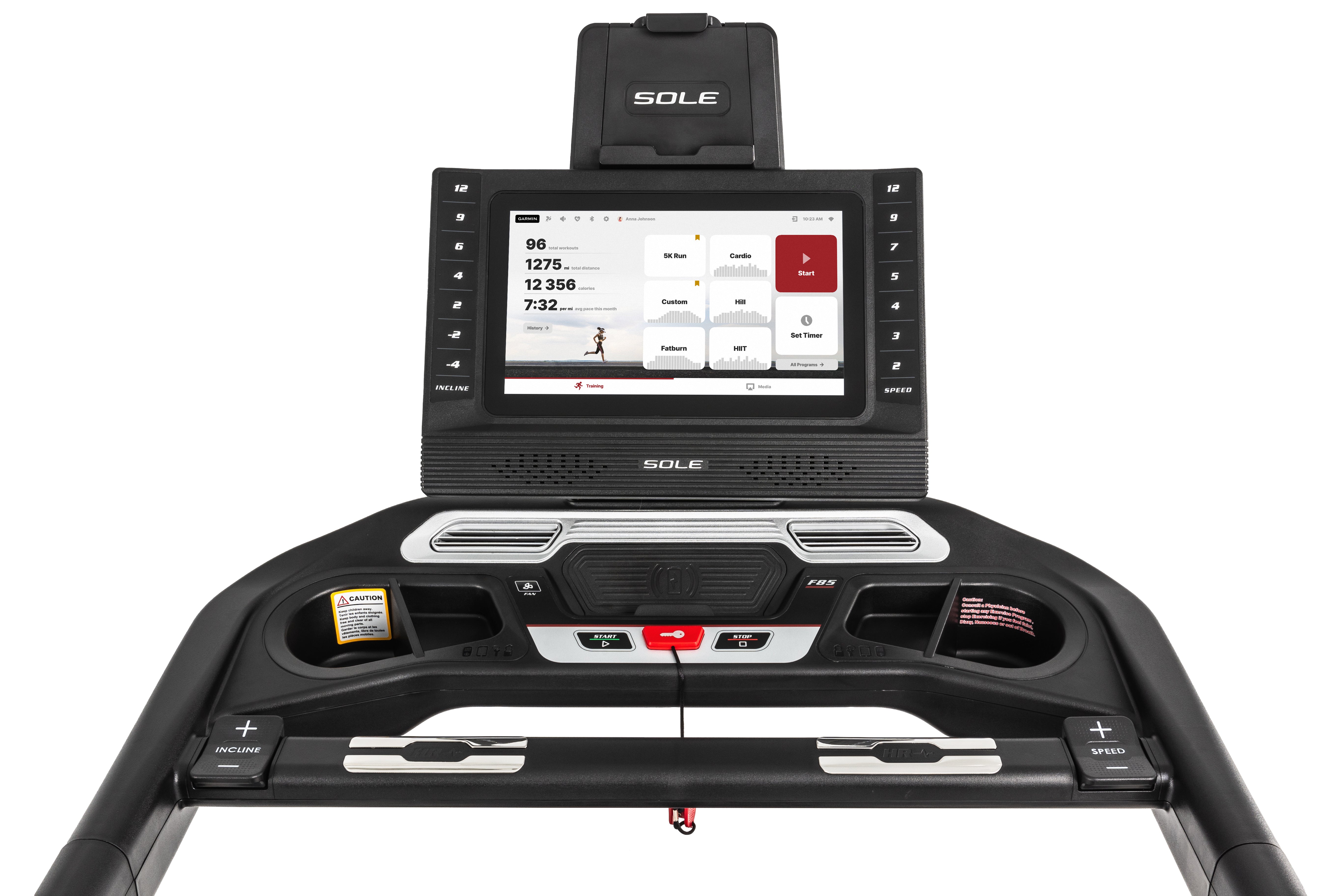 Top view of the Sole F85 treadmill console, featuring a digital display showing workout metrics, a tablet holder with the SOLE logo, and a black dashboard with controls for speed and incline adjustments, emergency stop, and labeled buttons for various functions.