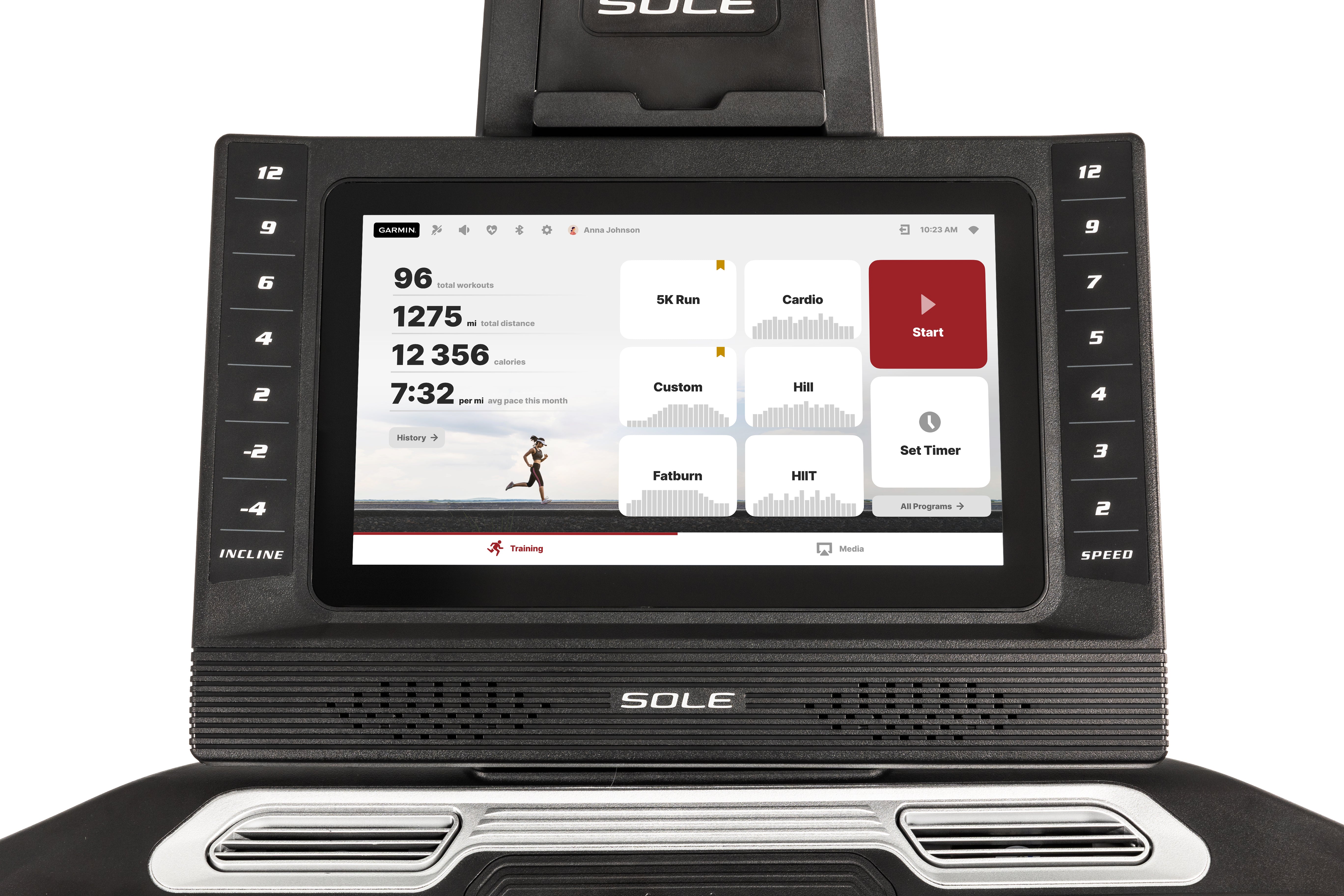 Front view of the Sole F85 treadmill's advanced digital display showcasing workout statistics, selectable training programs like "5K Run" and "HIIT", and touchscreen controls, flanked by incline and speed adjustment buttons, with the SOLE branding visible below the screen and air vents.