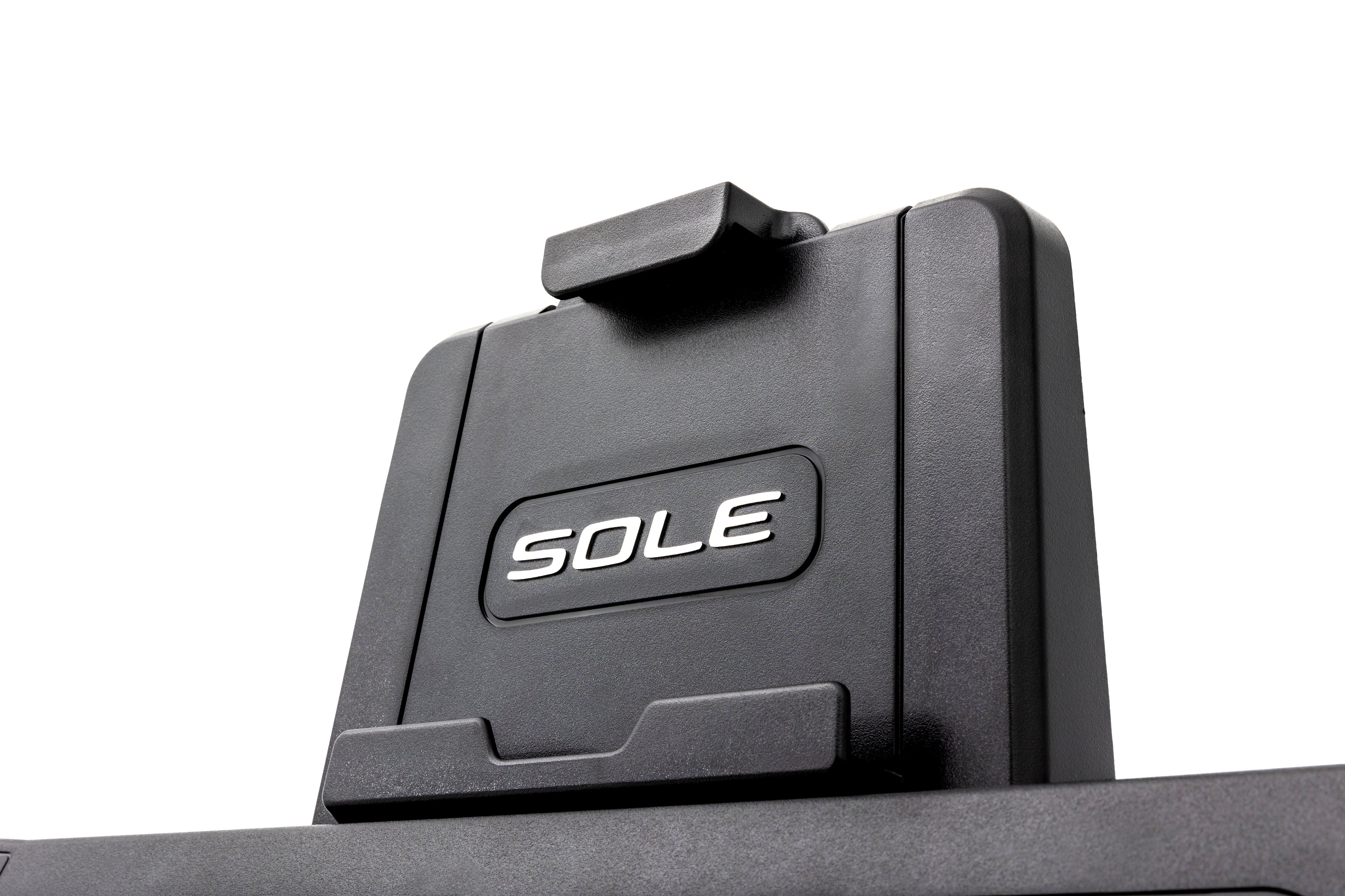 Detailed view of the Sole ST90 treadmill's tablet holder, emphasizing the embossed "SOLE" logo and textured black finish.
