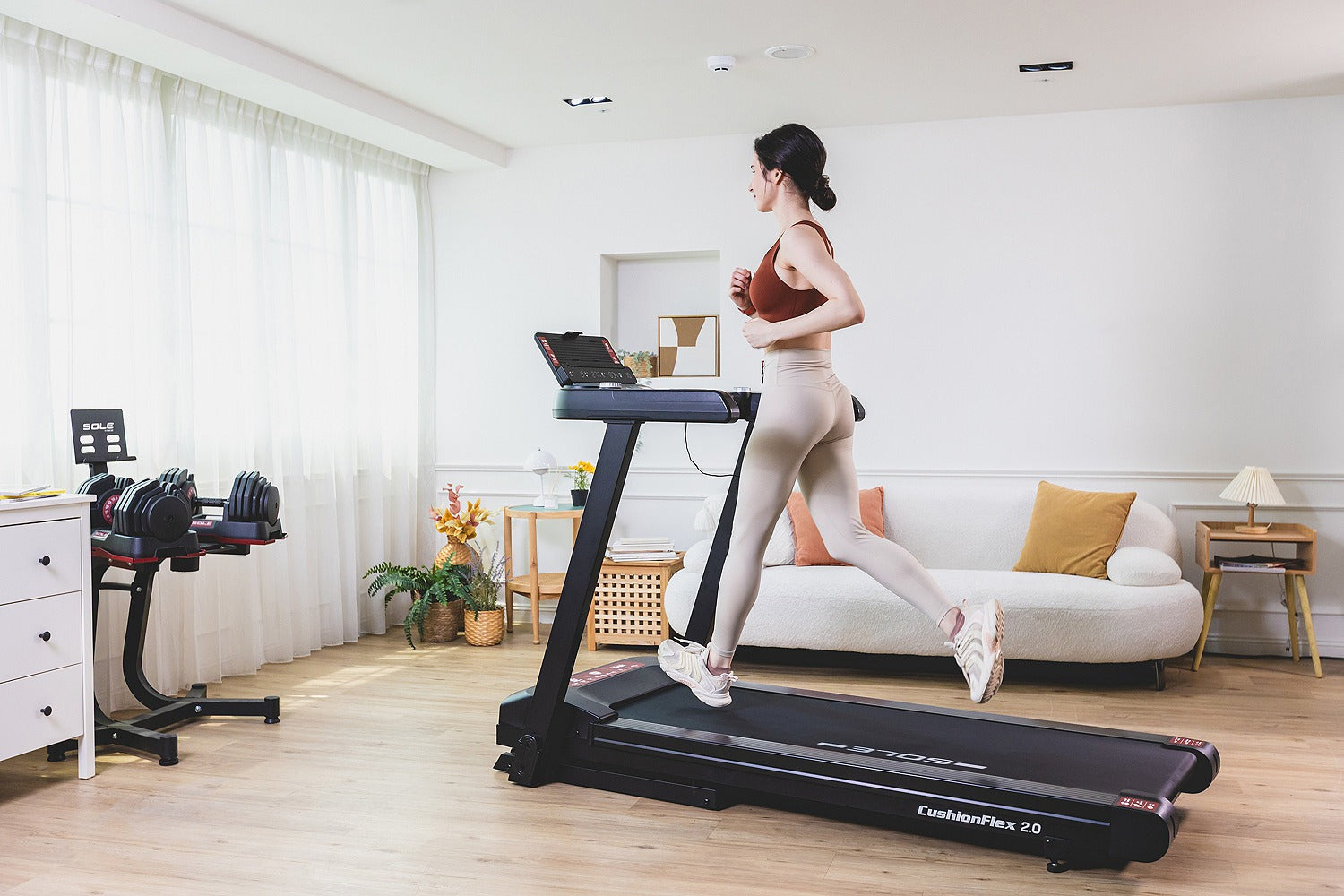 A runner training on the SOLE F63 treadmill in a bright home living room