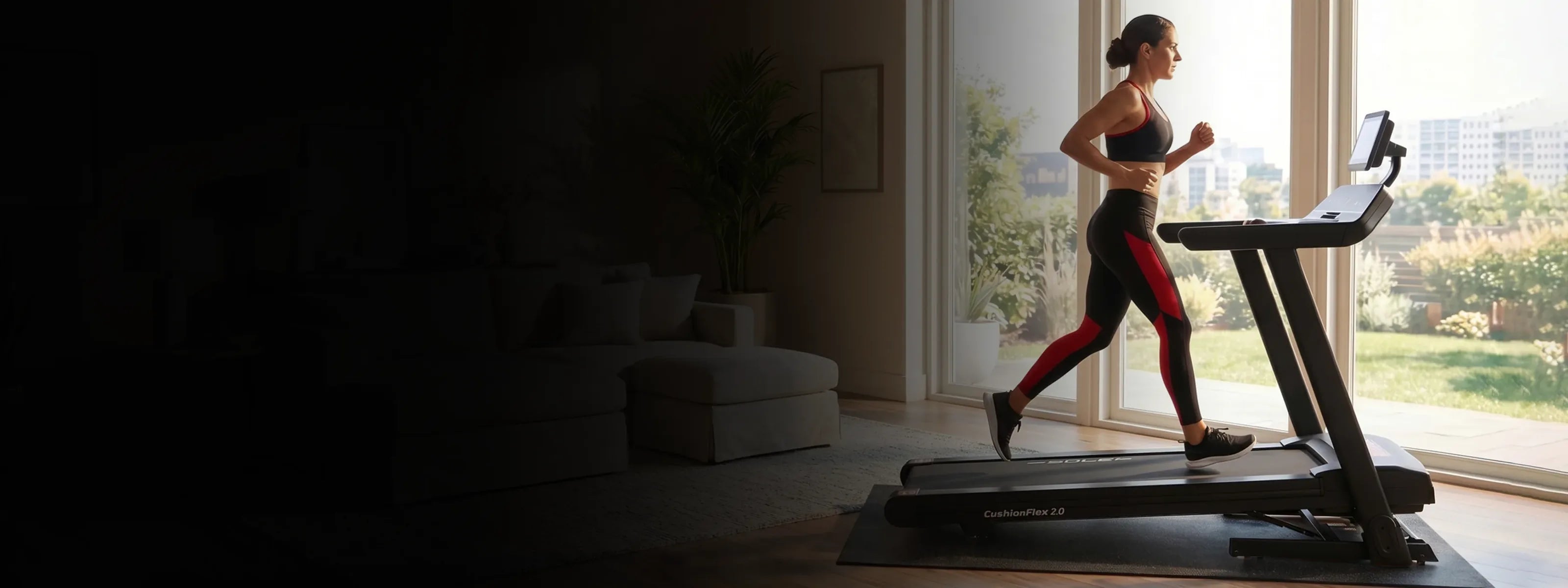 A woman running on the SOLE F80 treadmill in a sunlit living room with floor-to-ceiling windows onto a garden